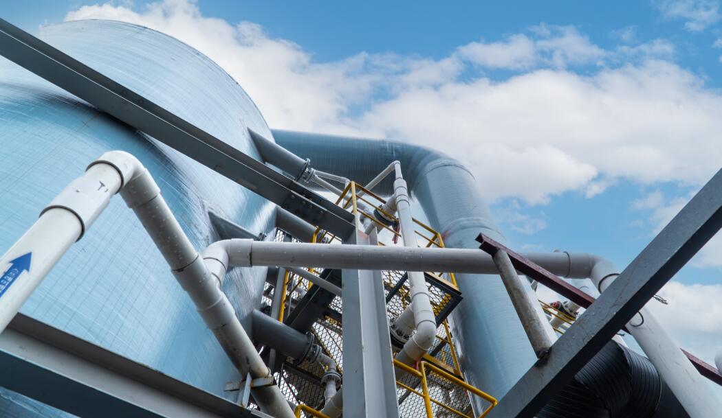 Industrial pipes and a tank under a blue sky